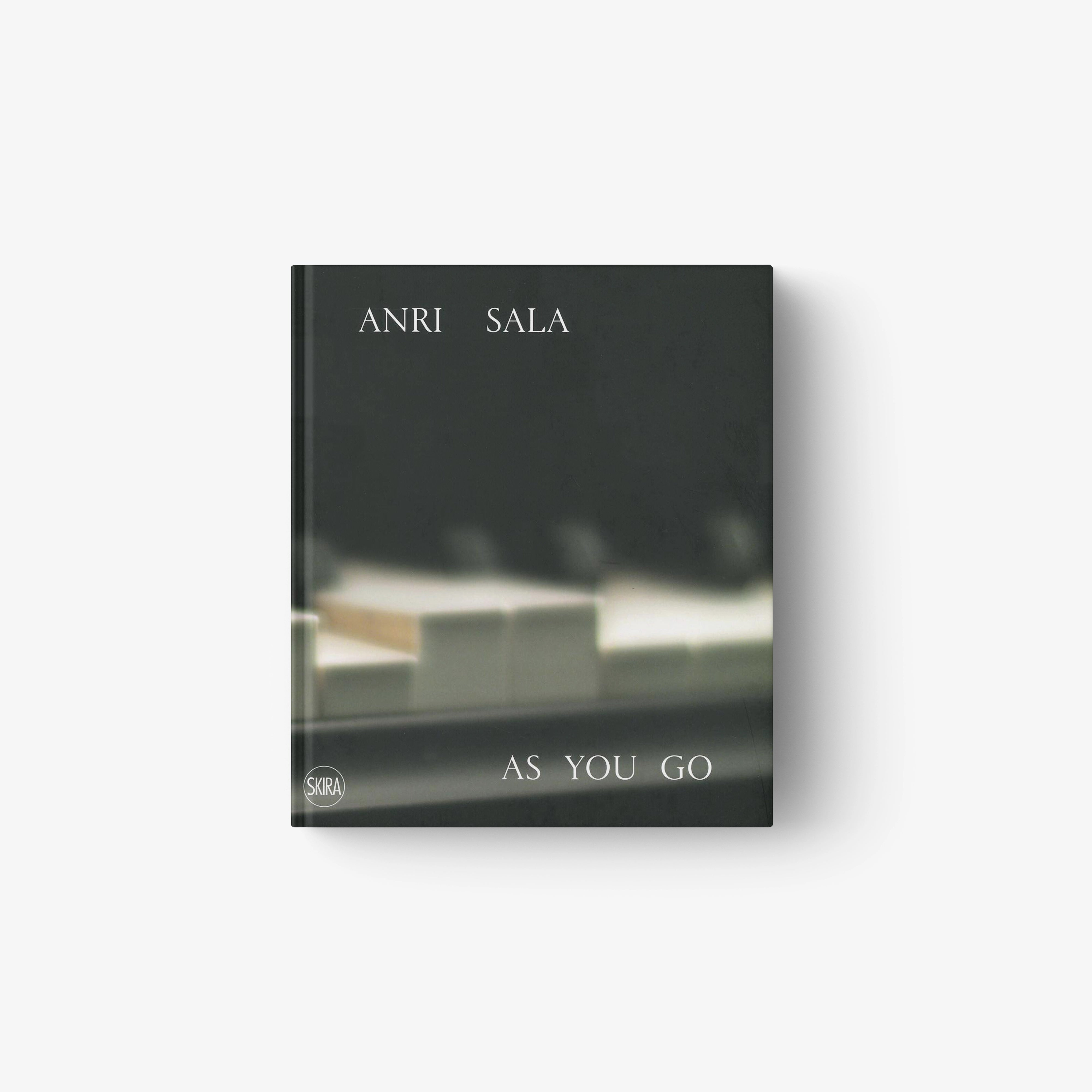 Dark-toned book cover featuring blurred piano keys with white text "ANRI SALA" and "AS YOU GO".
