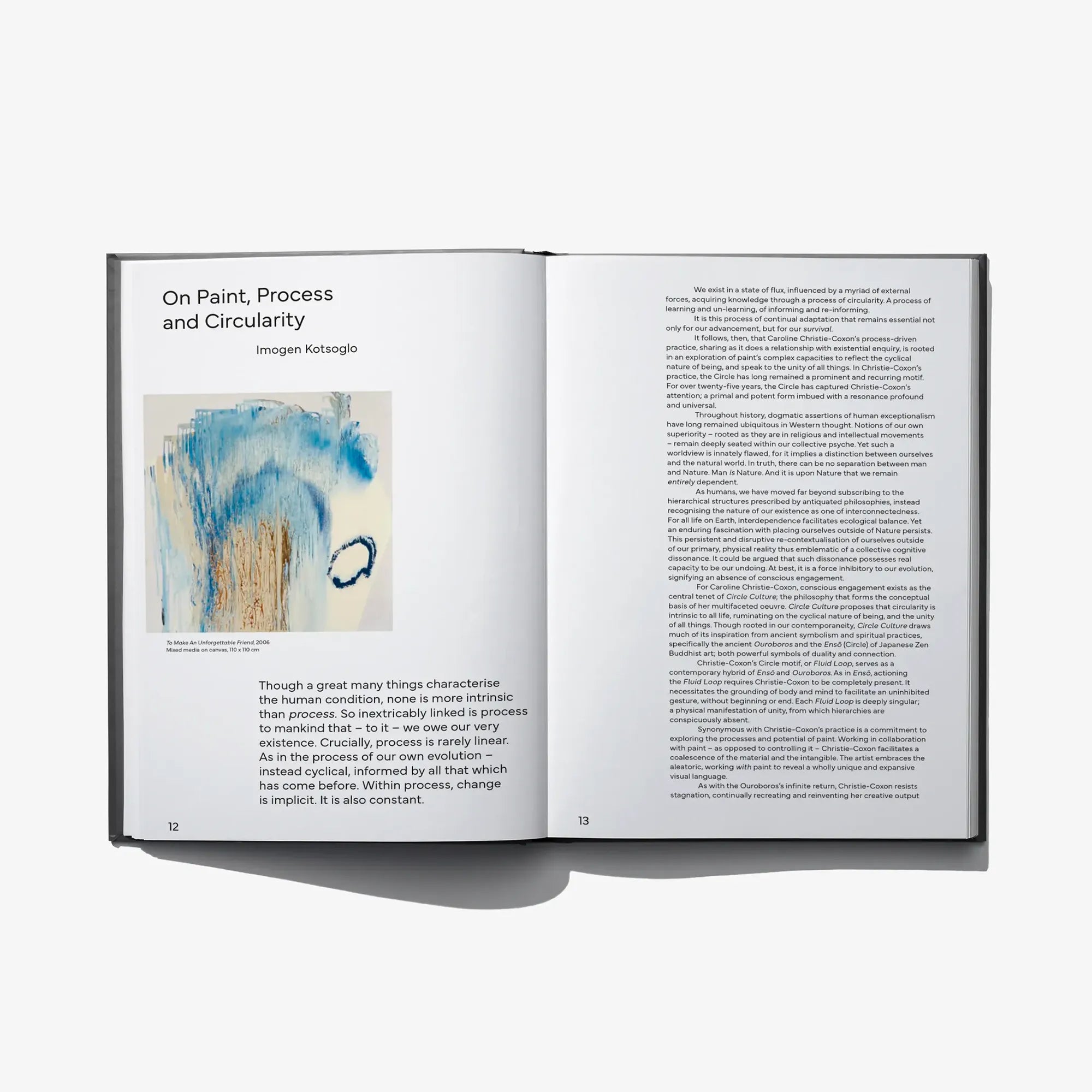 Open art book with blue abstract artwork on left and blocks of printed text on right