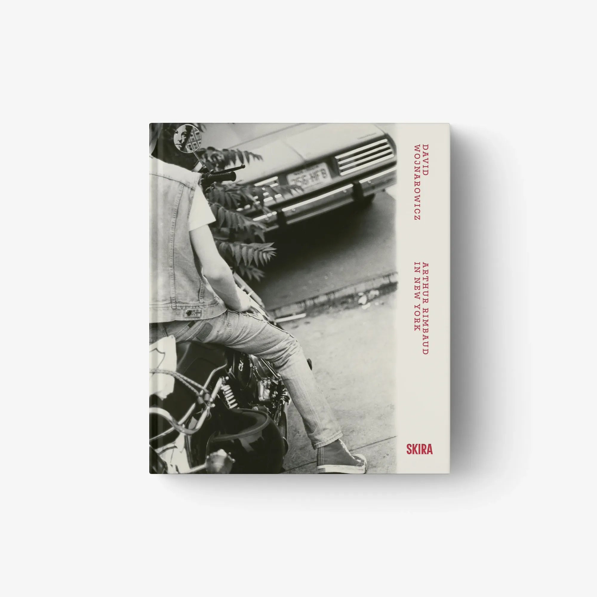 Grayscale photo book cover with person seated on motorcycle and red spine text