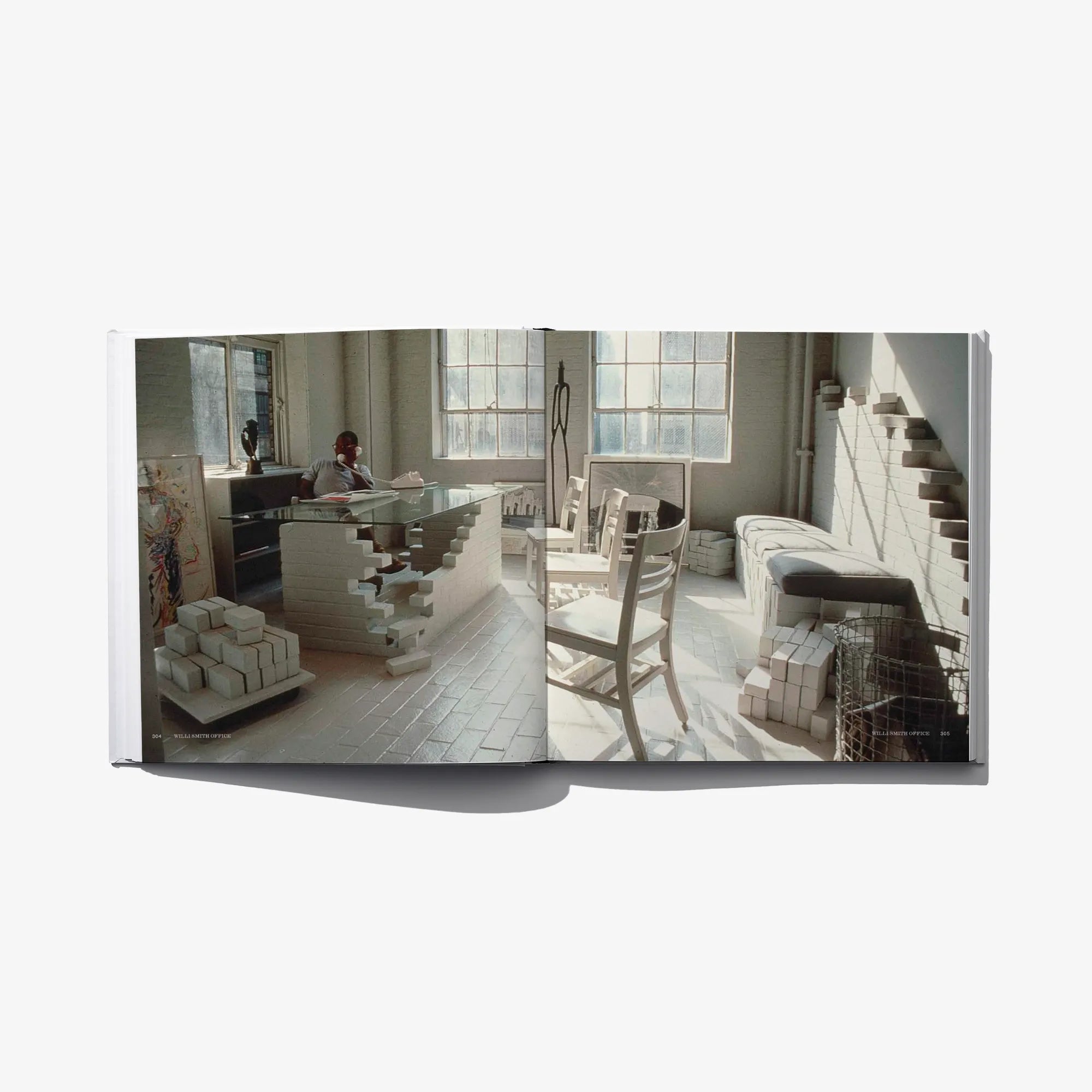 Open book page with a photo of an office/model room and stacked furniture models