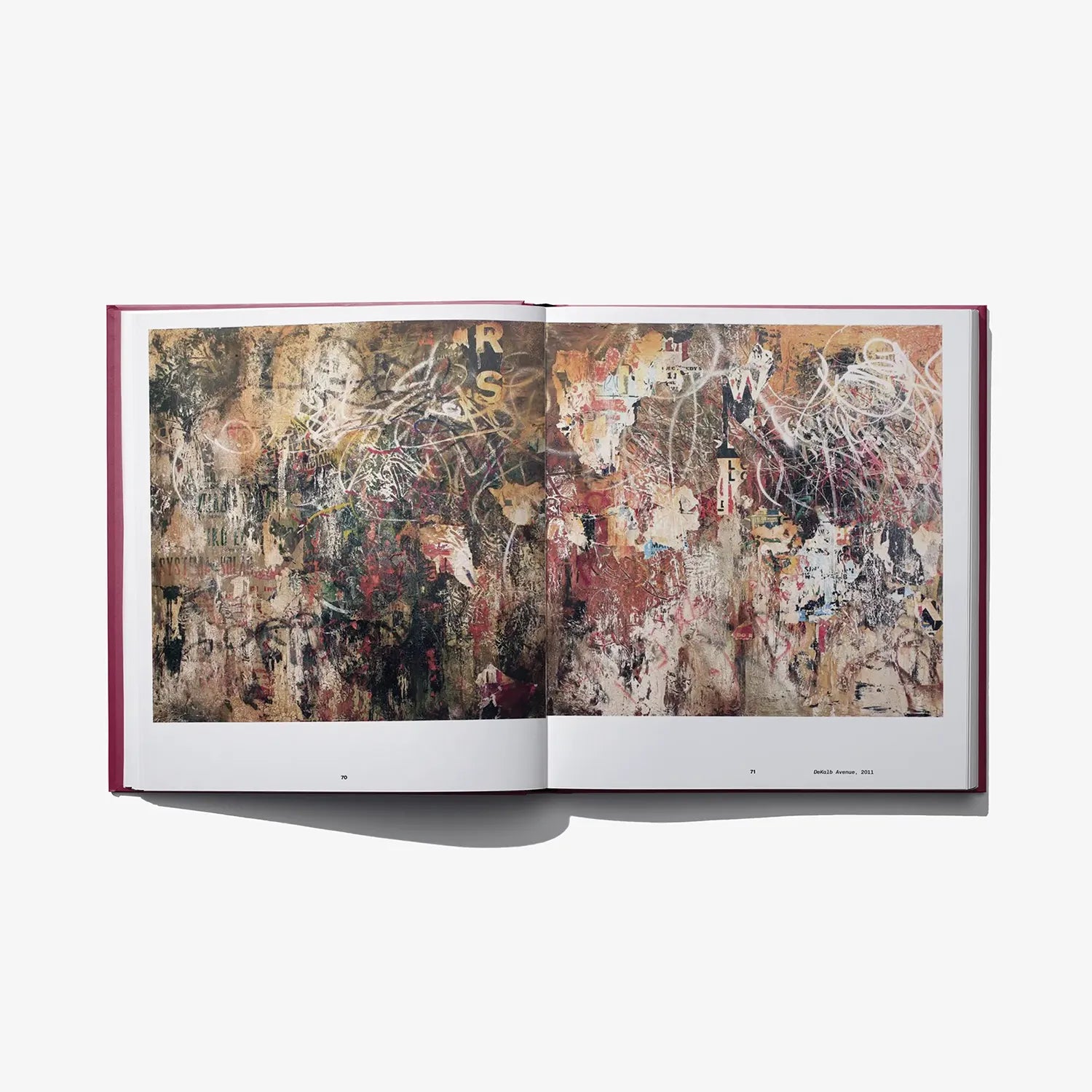 Open hardcover art book with two-page abstract collage artwork and red binding