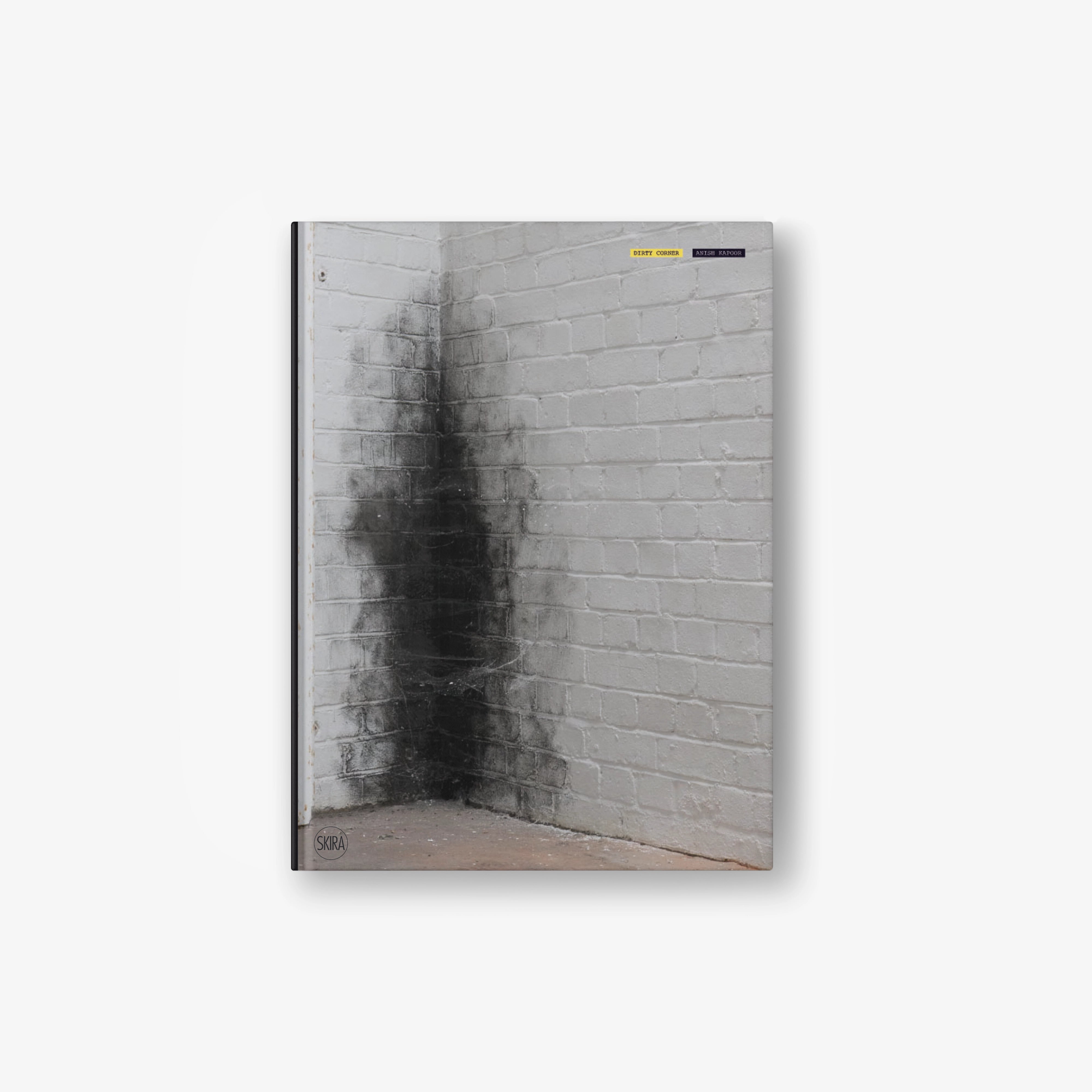 Hardcover art book cover with gray brick wall and dark corner stain