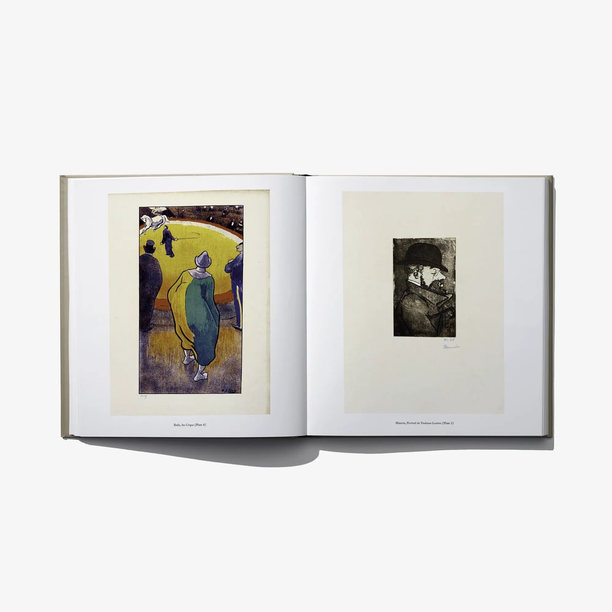 Open hardcover book showing two framed graphic prints on cream pages