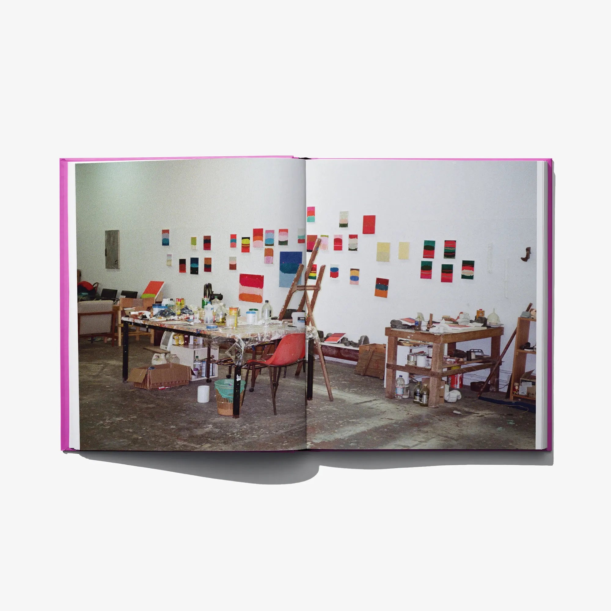 Open art book showing a studio scene photo on the right page