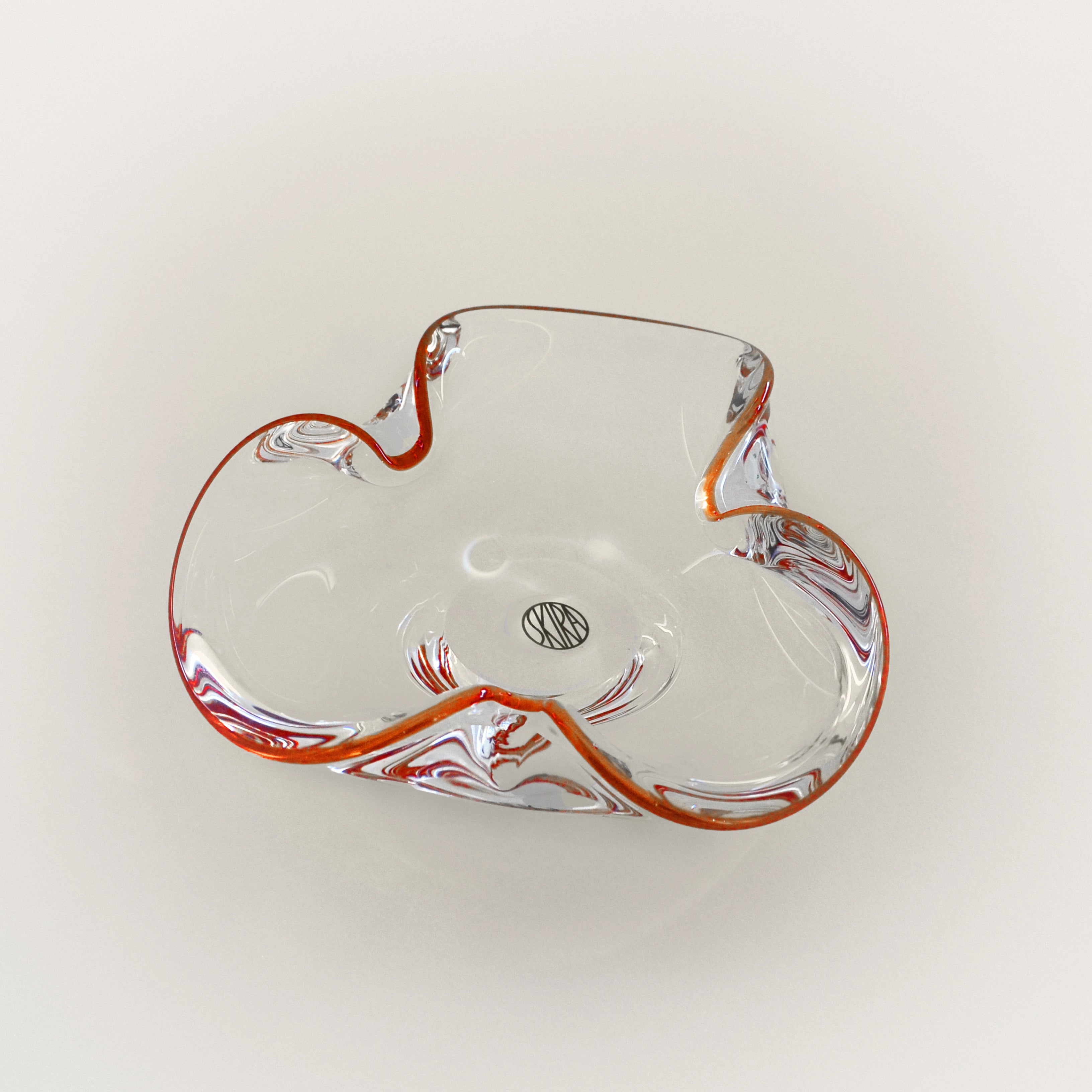 Clear glass tray with red accents, curved leaf shape and small center emblem