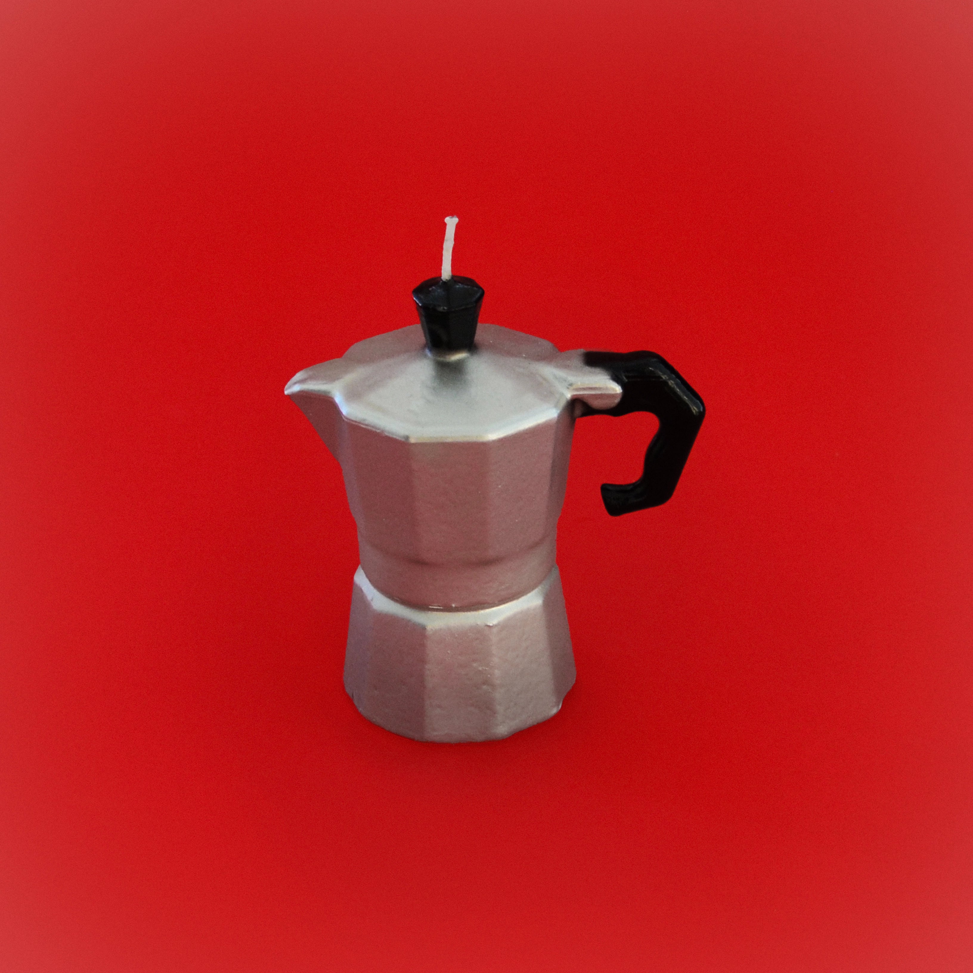 Coffee pot-shaped candle with silver body, black lid and spout, small wick on top