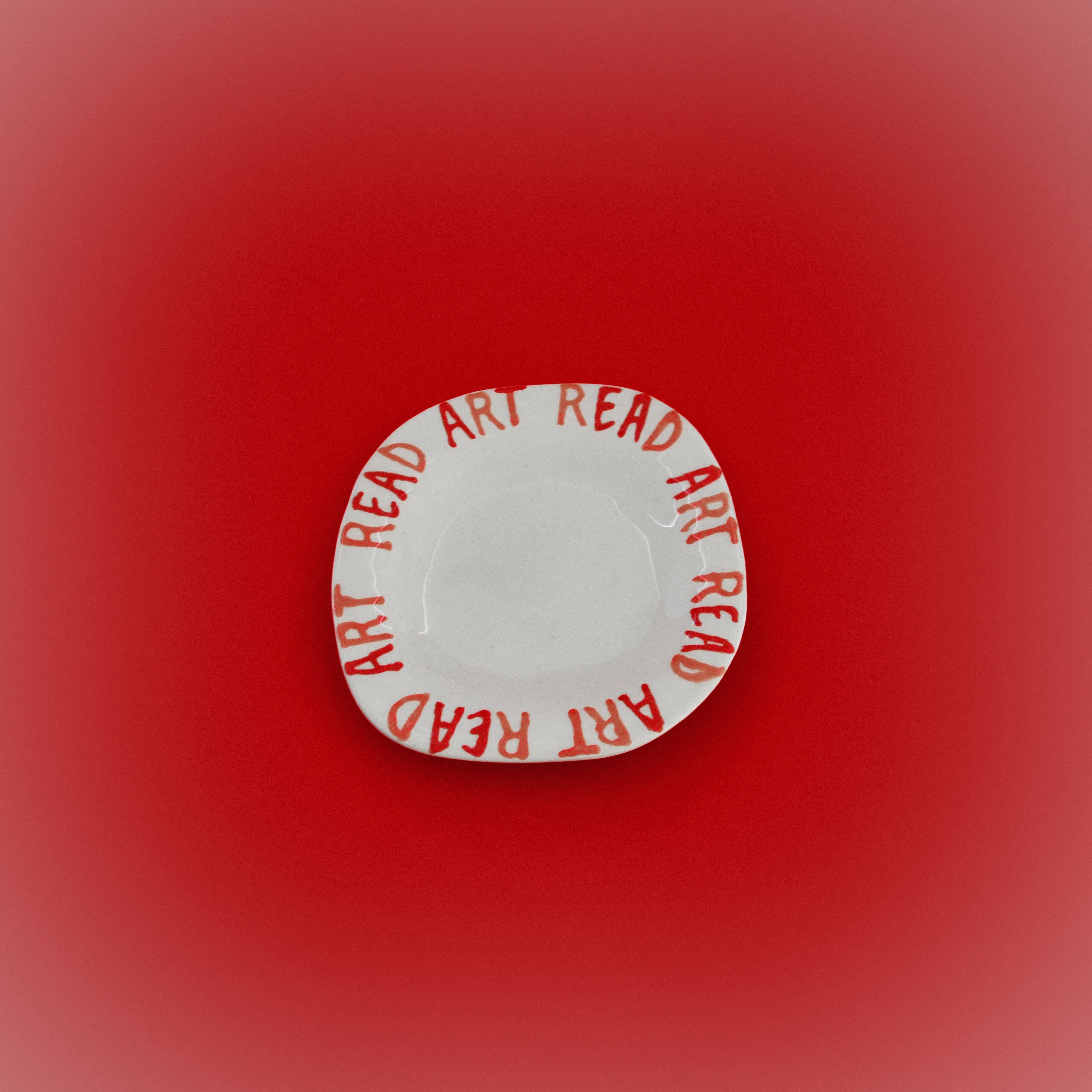 Round white ceramic dish with red ART READY text rim
