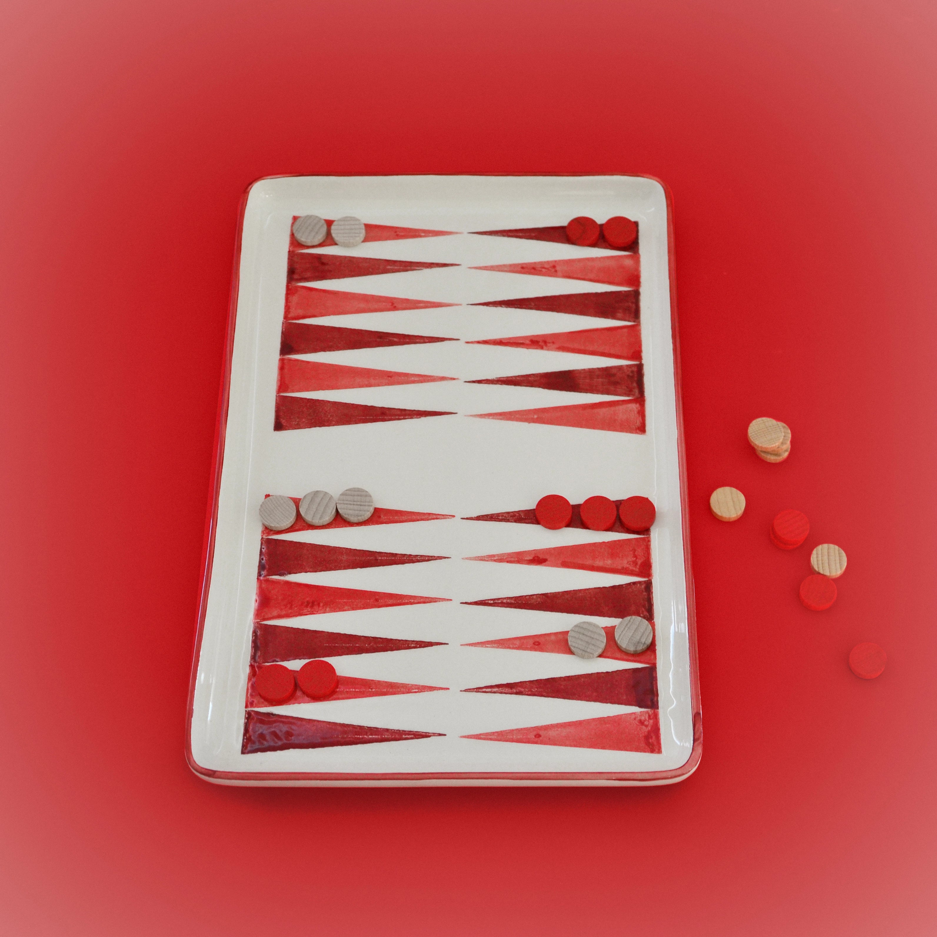 Handcrafted ceramic backgammon board with red-and-white checkers and playing pieces
