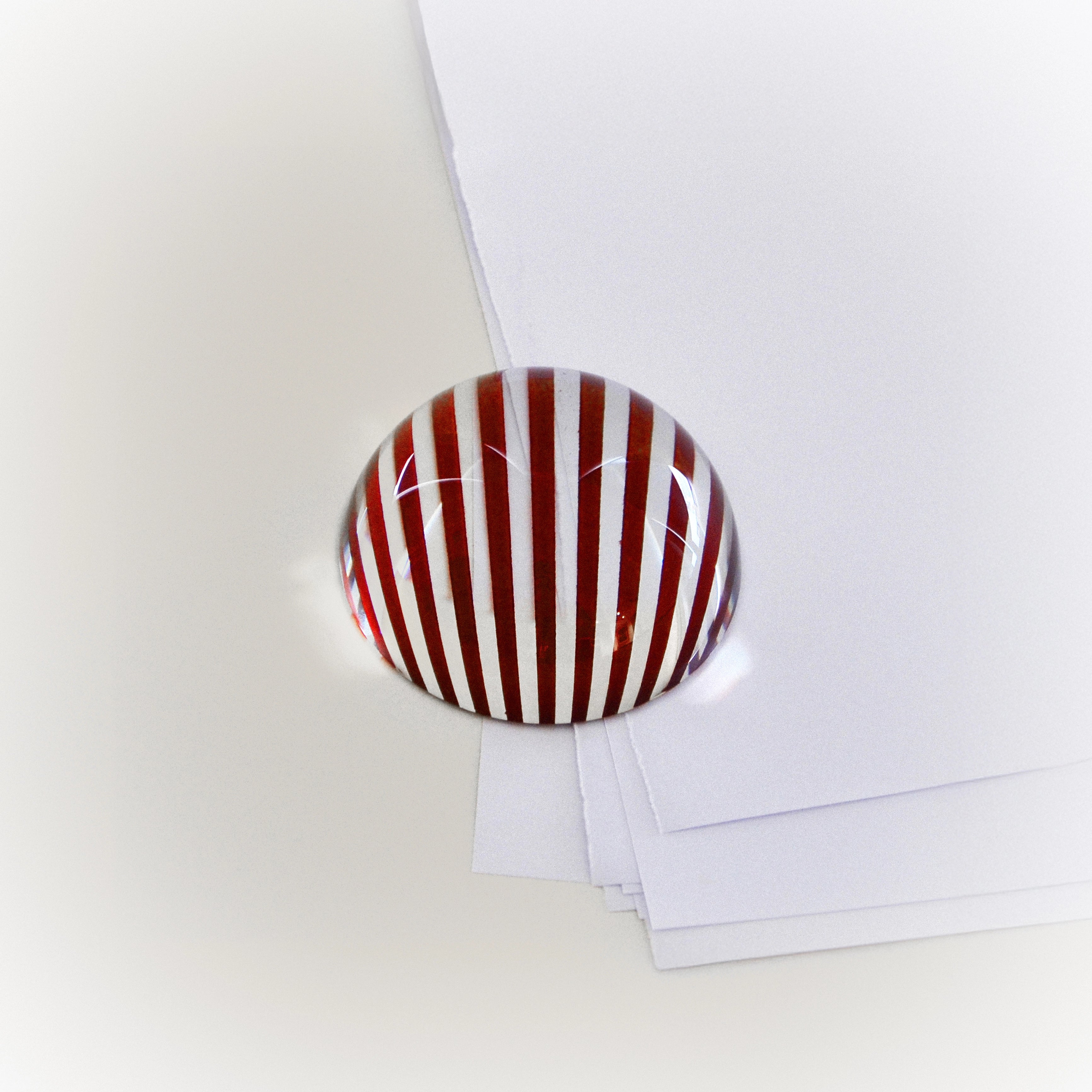 Brera striped red-and-white oval paperweight on papers