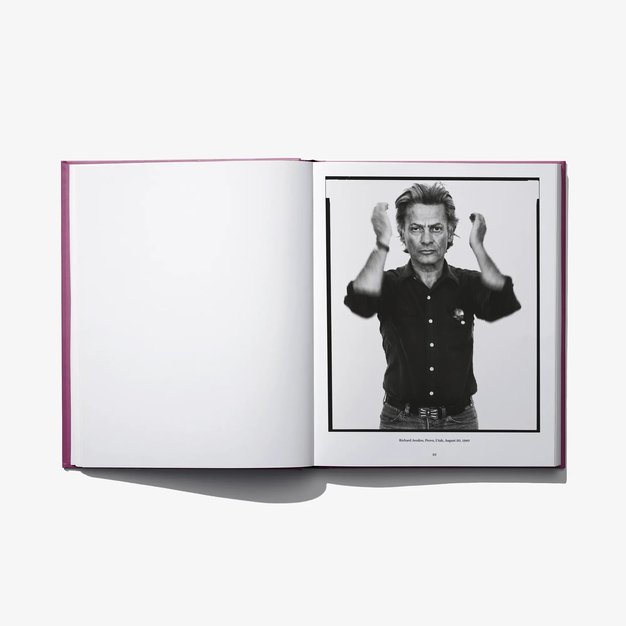 Open photo book showing a black-and-white portrait of a man with hands raised