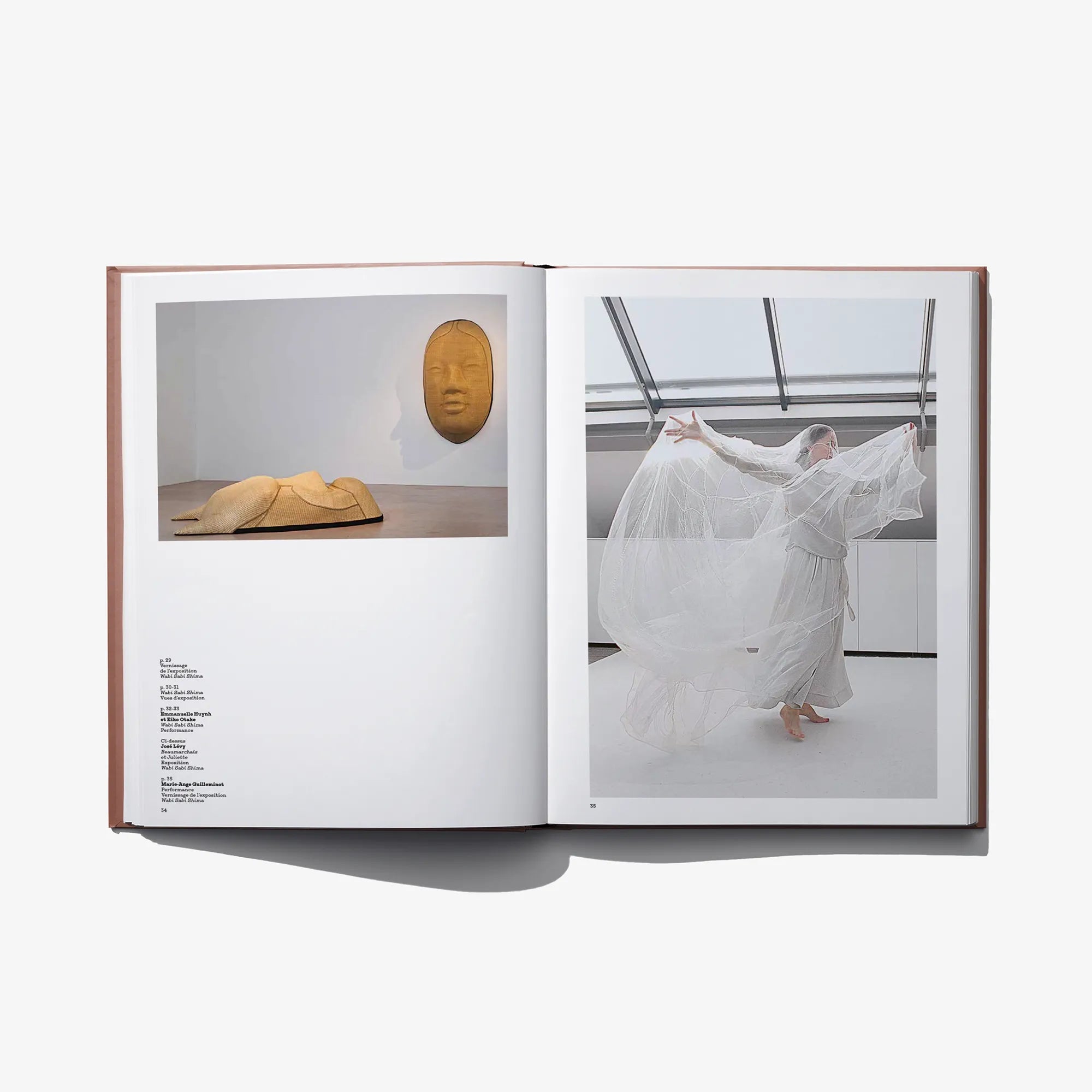 Open art book showing sculptures and a white tulle dress display in museum setting