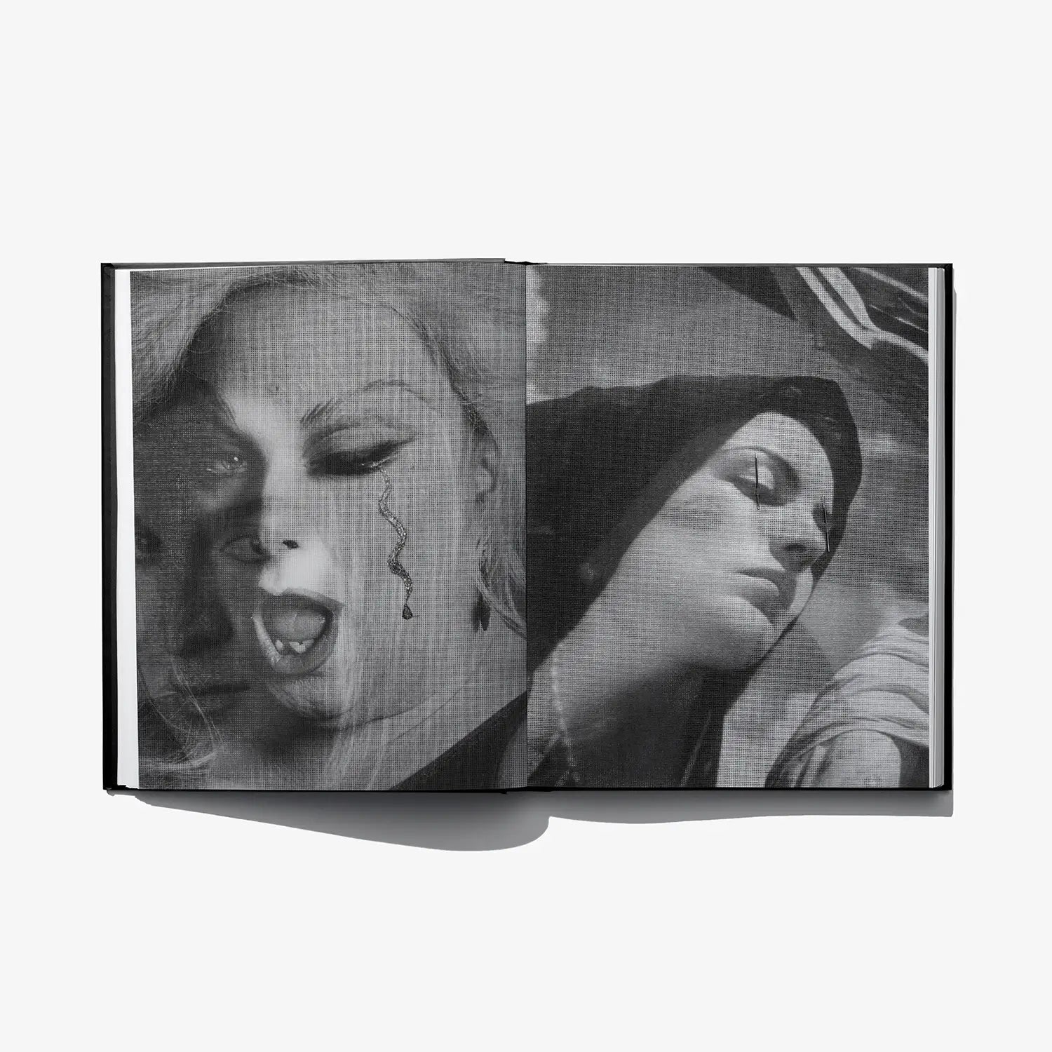 Open art book spread with monochrome face collage and stylized eye details