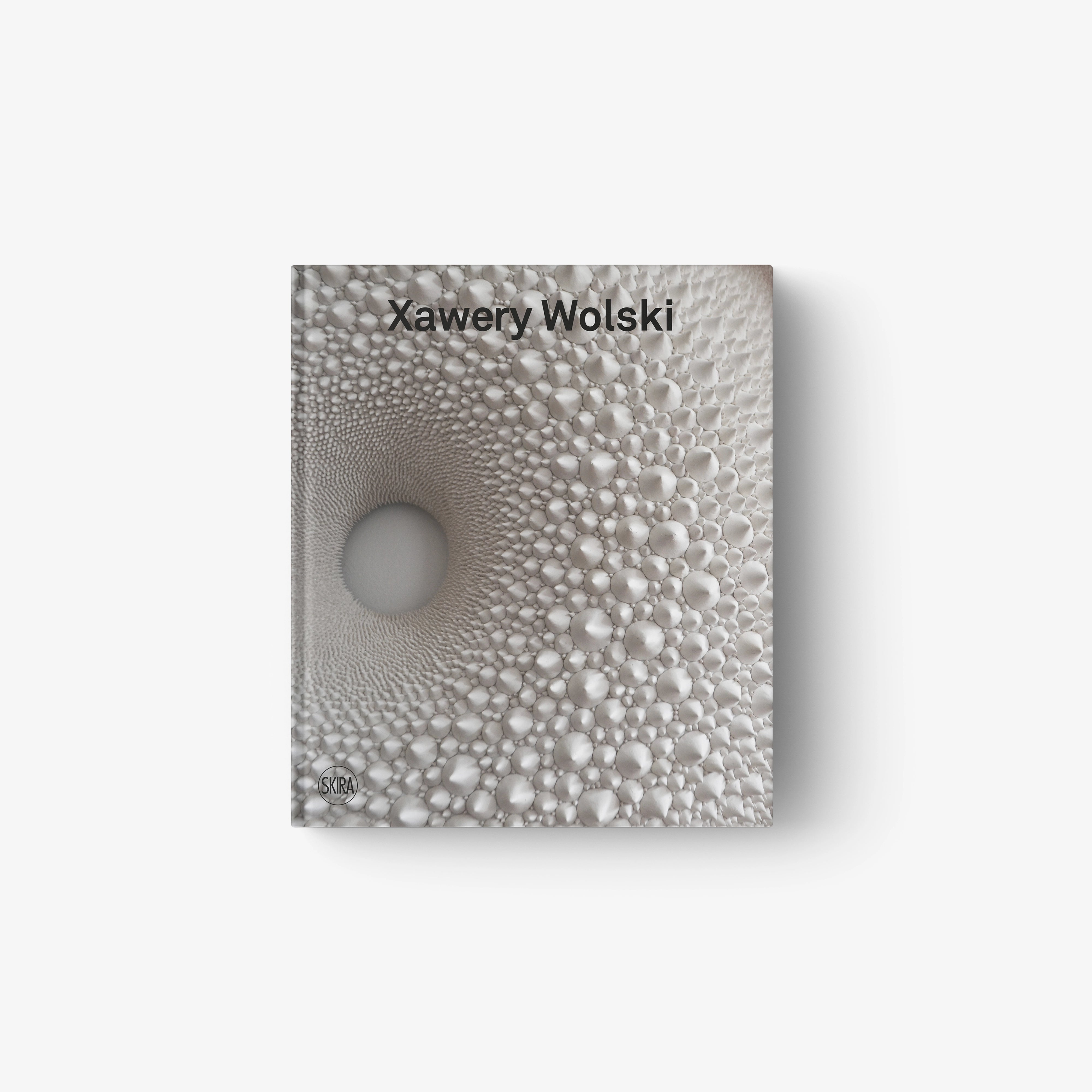 Textured gray sculpture with concentric raised bubbles forming a spiral pattern.