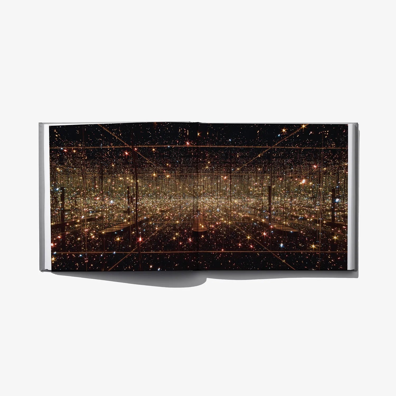 Open art book spread with dark scene of glowing golden dots and lines